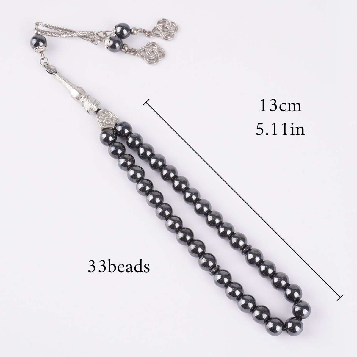 Close-up of silver arabesque Imame and braided chain tassel on black obsidian tasbeeh