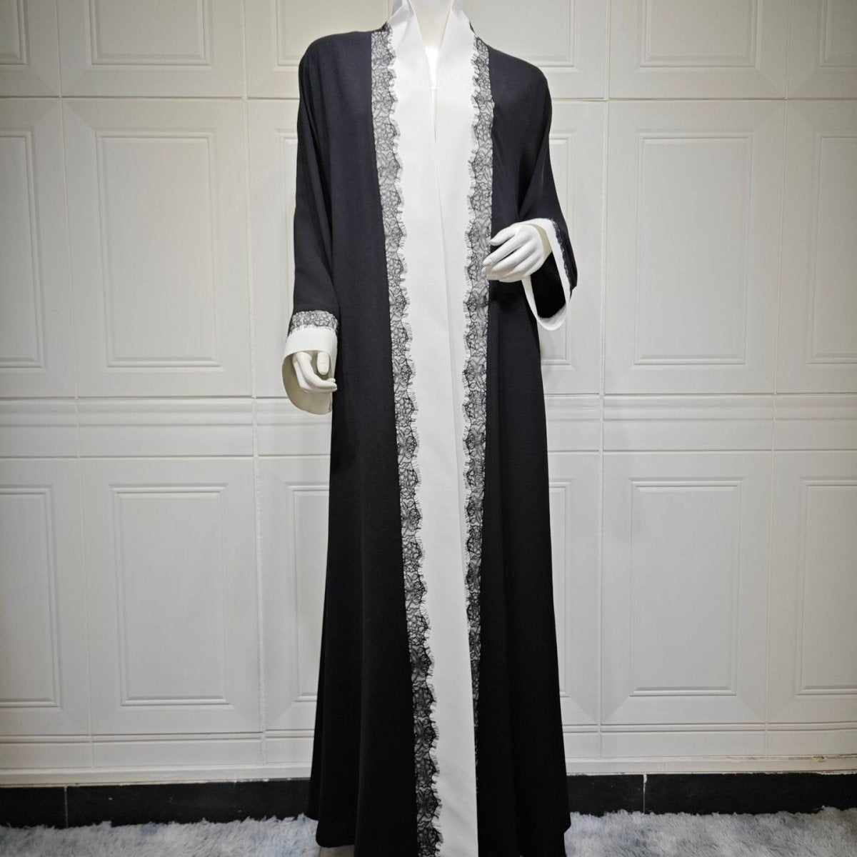 Detail of white lace-trimmed wide cuffs on black open abaya