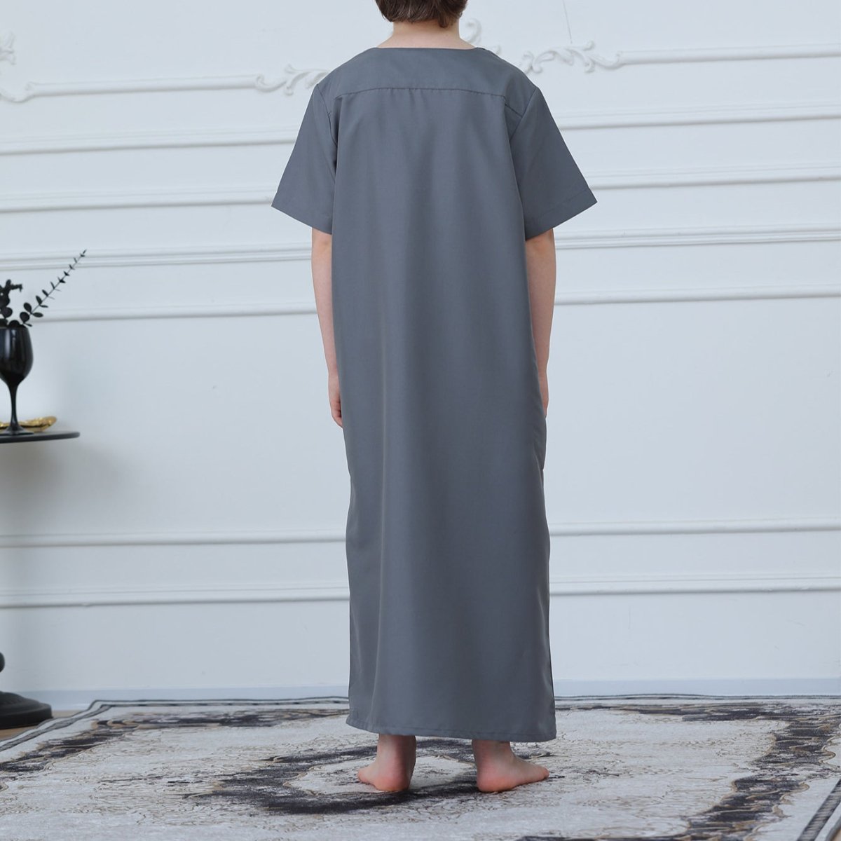 Close-up of tonal rope and scroll embroidery on charcoal gray boys' thobe placket
