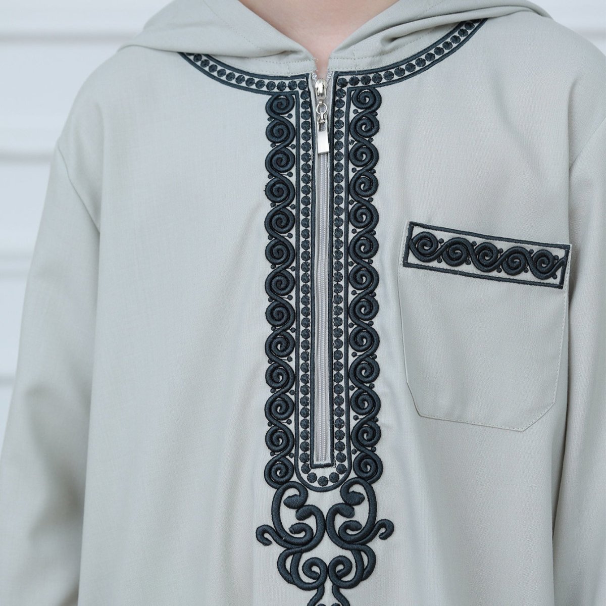 Close-up of spiral and geometric embroidery on boys' thobe chest placket