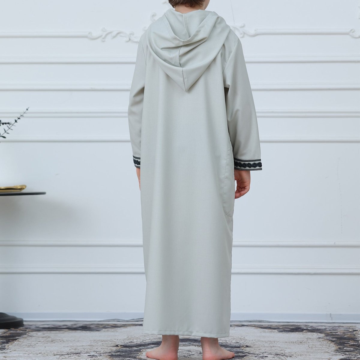 Front view of boys' sage gray thobe showing dark green geometric embroidery panel