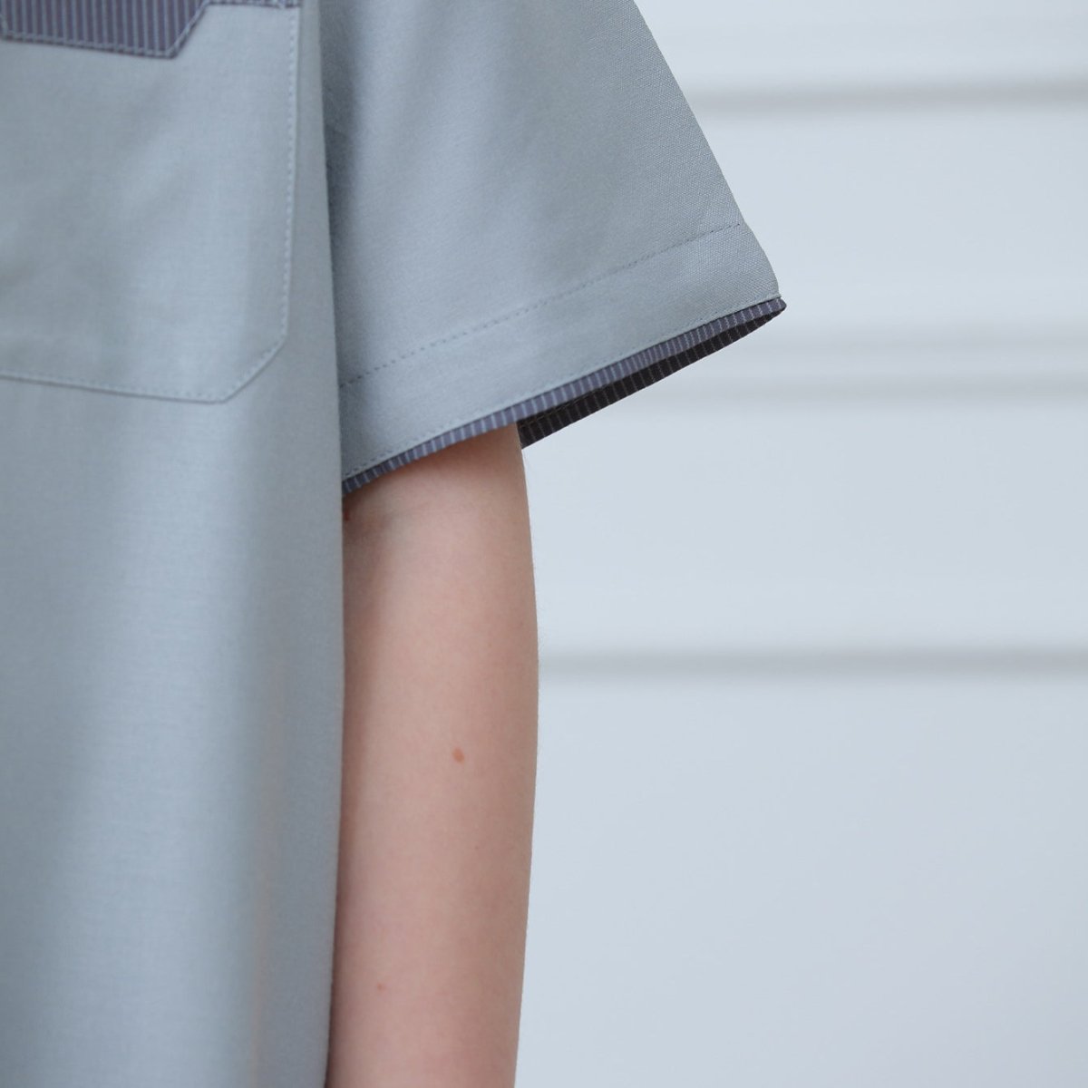 Side view of ankle-length boys' thobe with contrast trim short sleeves