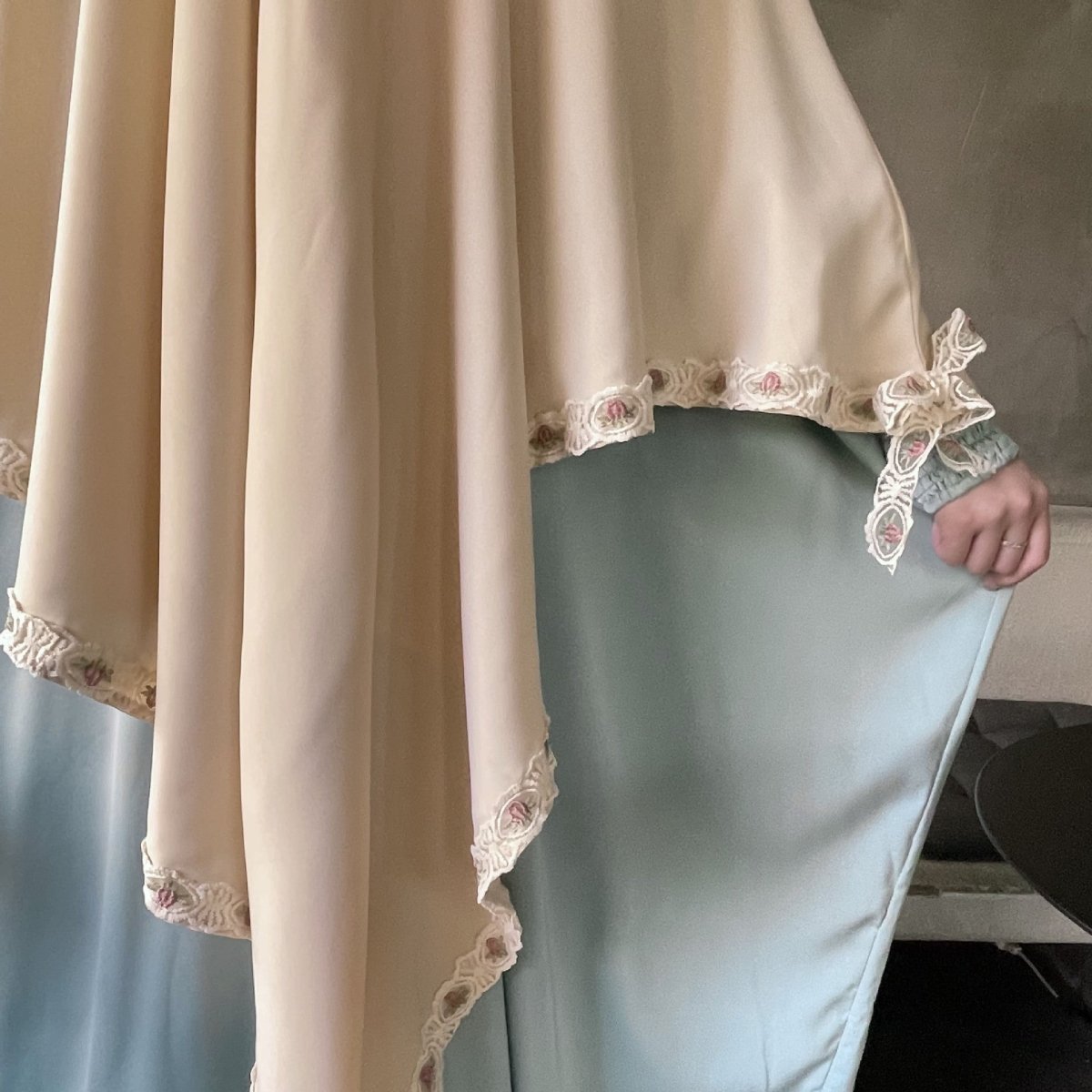 Close-up of scalloped floral lace trim with pink and sage embroidery