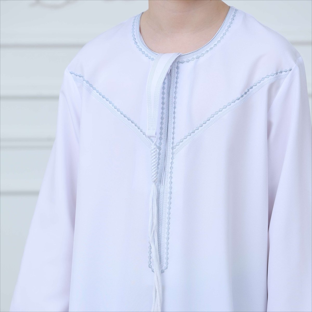 Close-up of gray contrast stitching on white kaftan thobe yoke