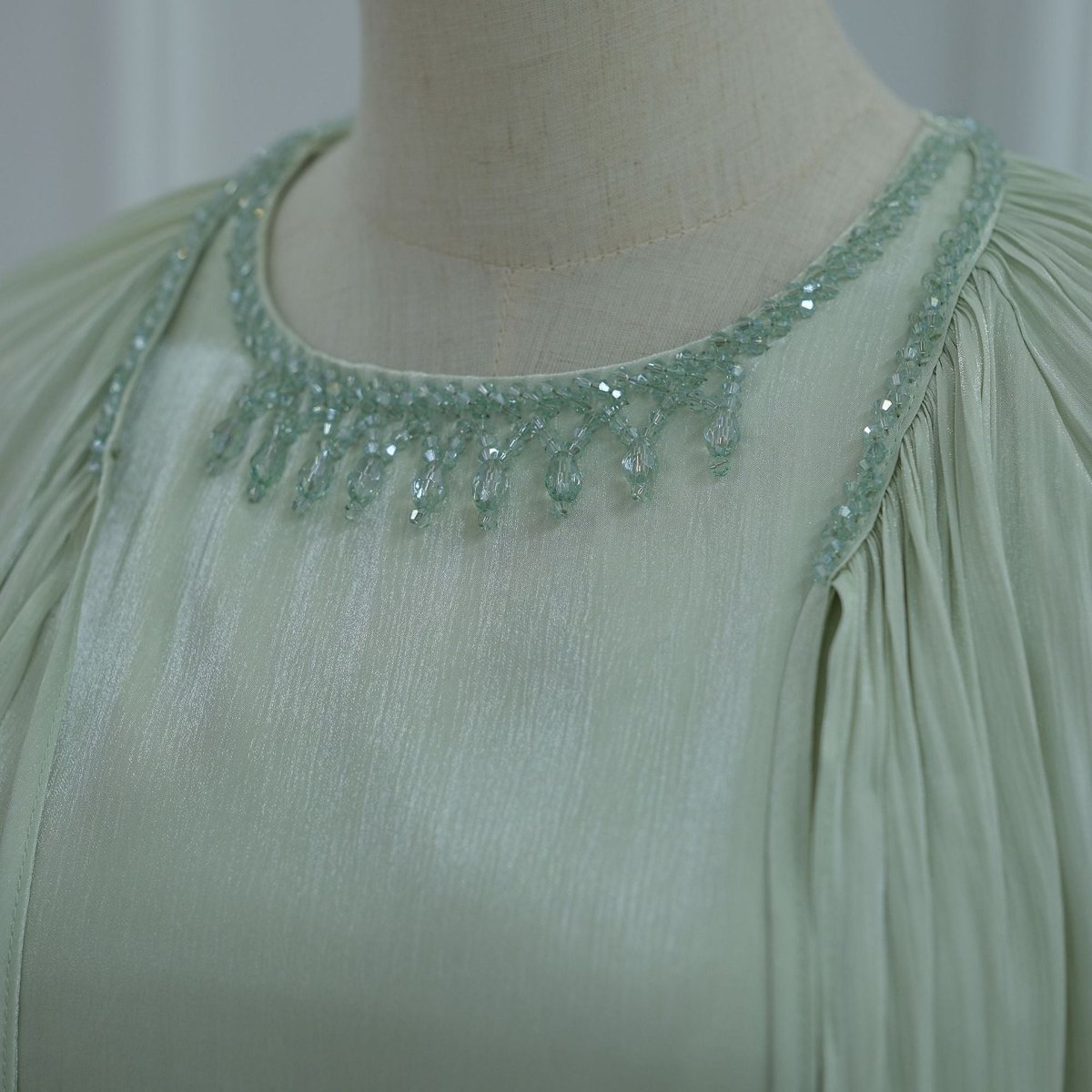 Close-up of hand-embellished crystal bead neckline against smooth fitted bodice
