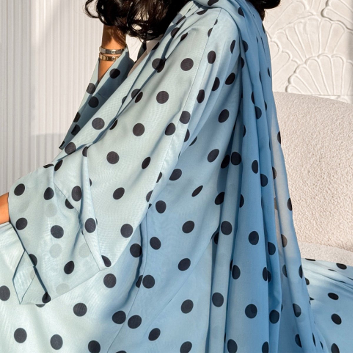 Model seated wearing 2-piece polka dot abaya with matching hijab