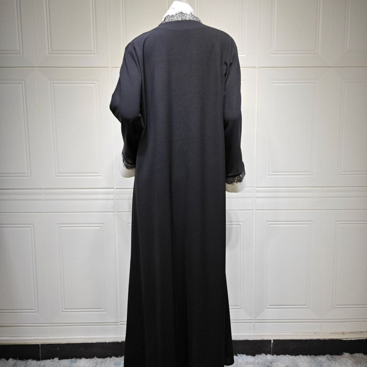 Layered styling shot of black and white lace abaya worn over an inner dress