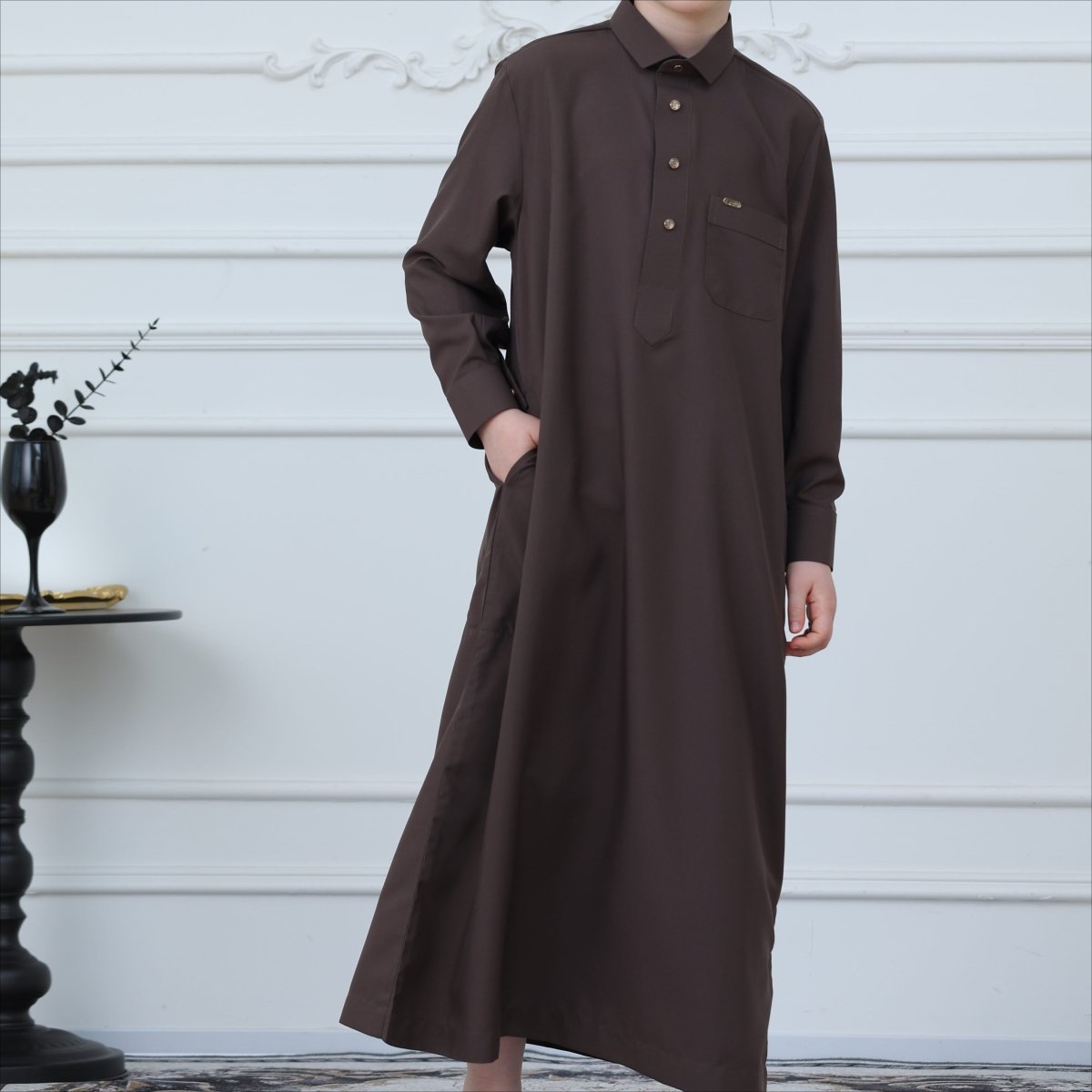 Close-up of pointed collar and metal button placket on chocolate brown boys thobe