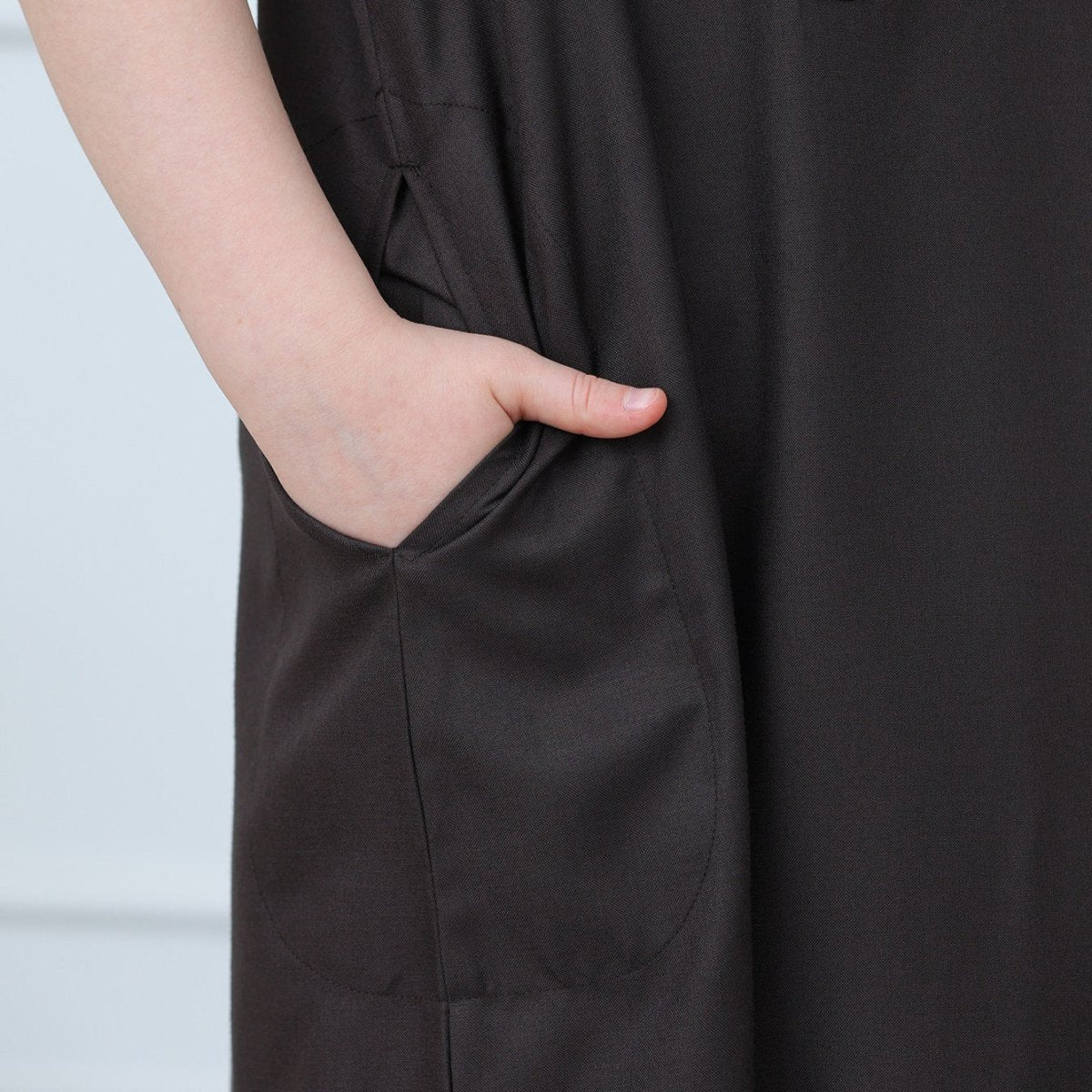 Full-length back view of boys' black poly-cotton thobe with embroidered trim