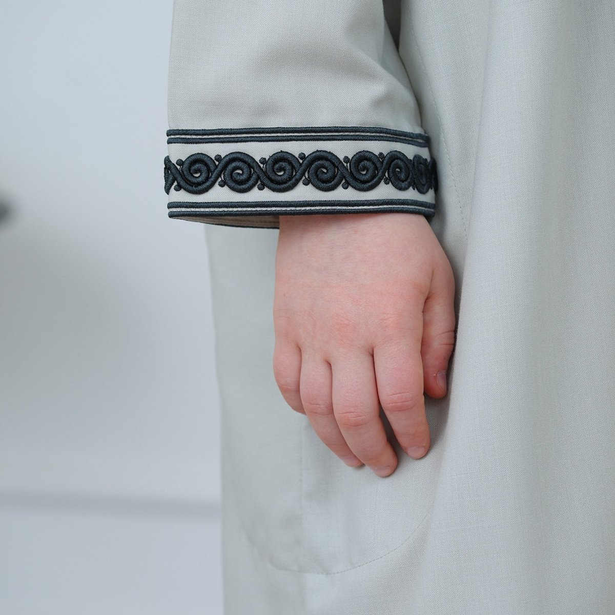 Side view of boys' ankle-length hooded thobe with pockets