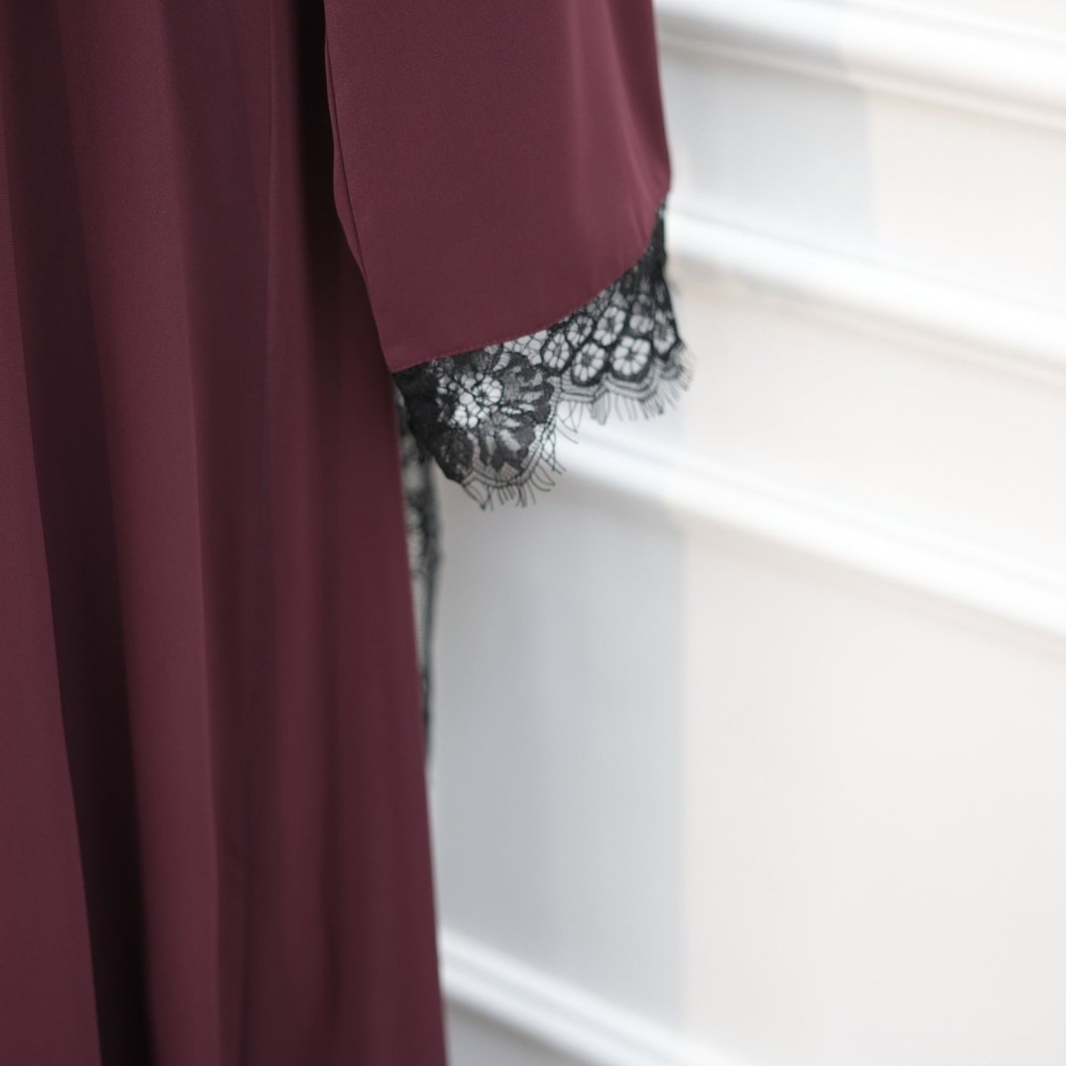 Overhead flat-lay showing asymmetric lace panel and long sleeve maxi dress construction
